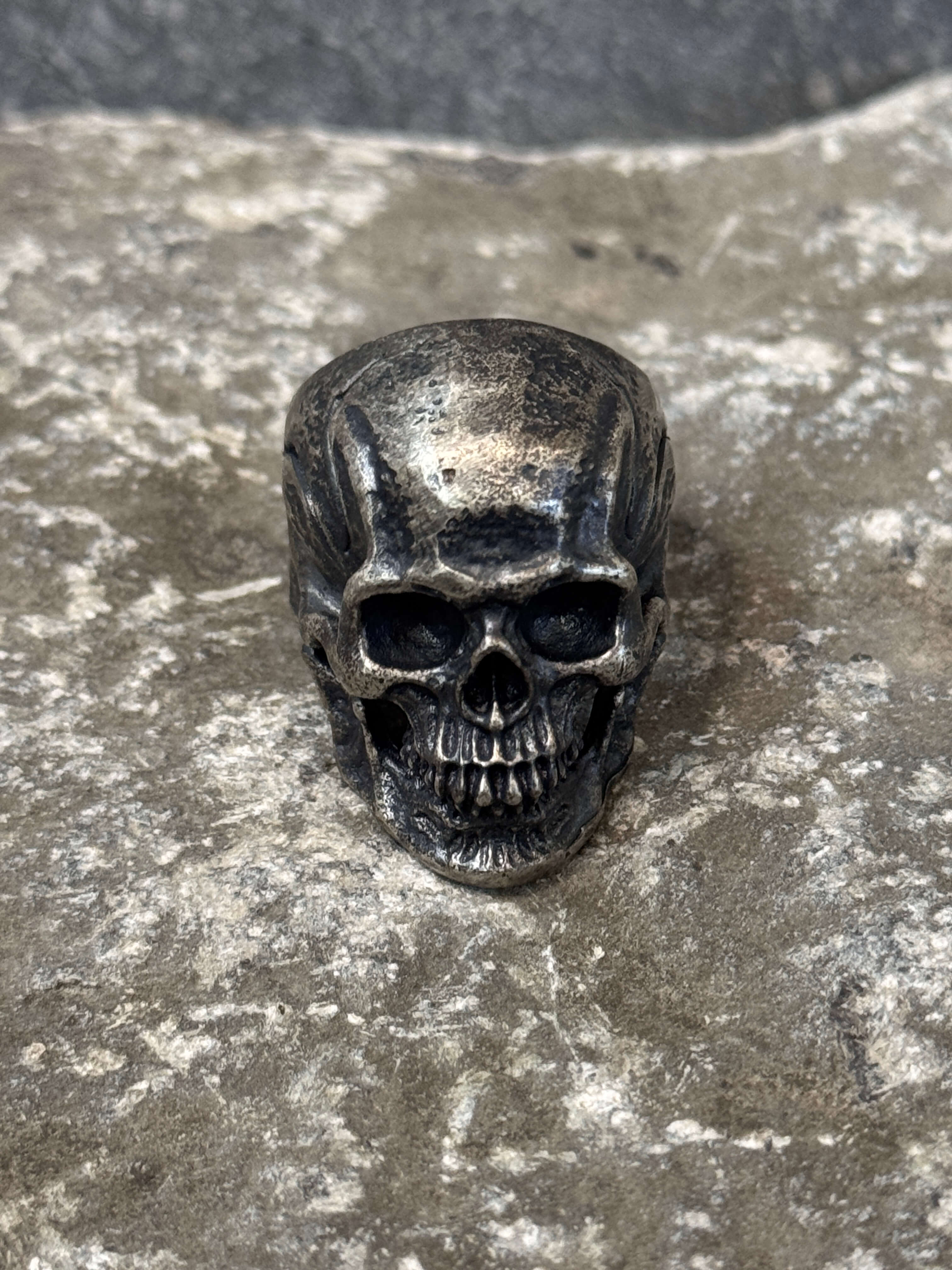 Skull-shaped ring on a textured stone surface