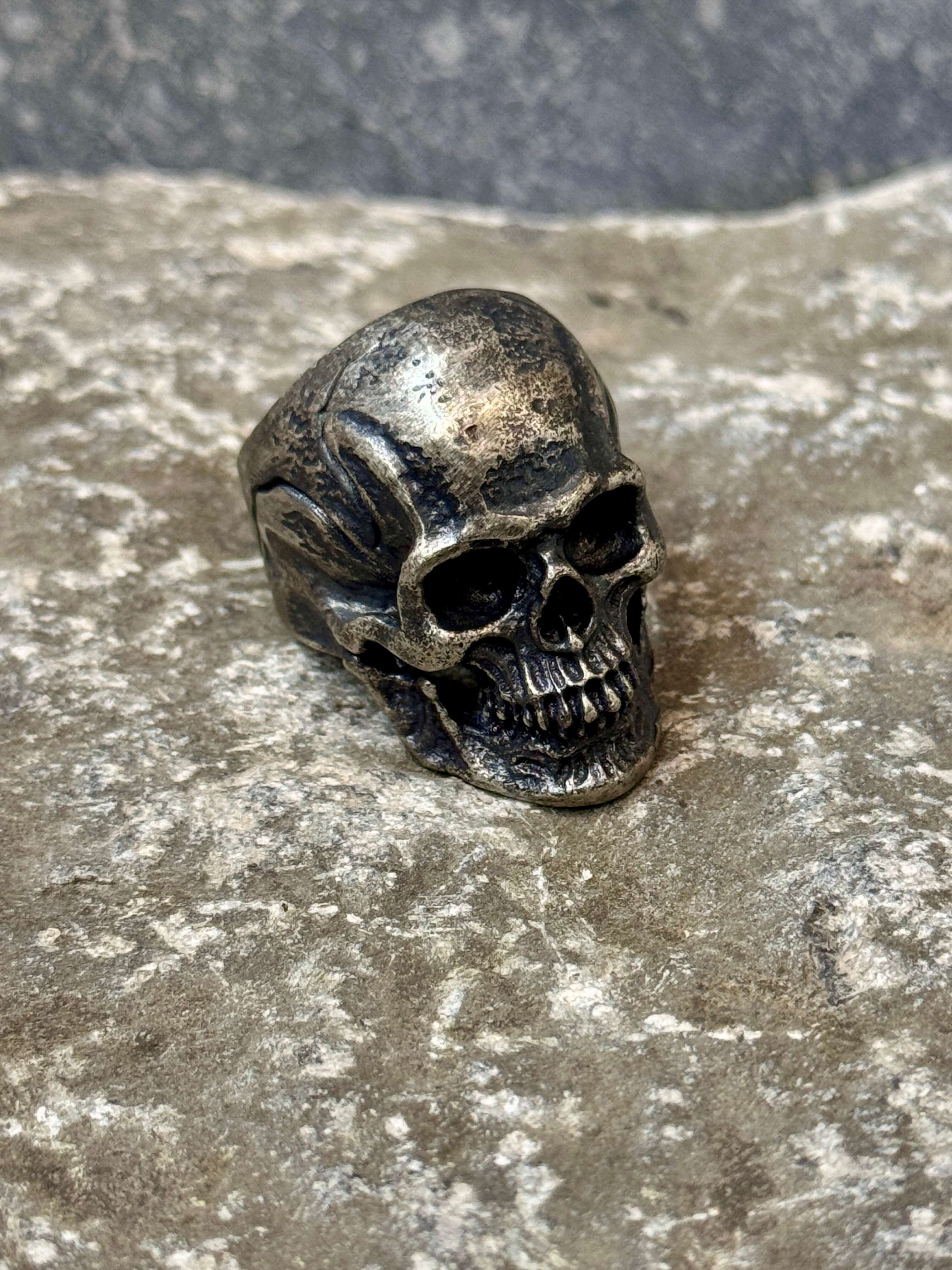 Skull-shaped ring on a textured stone surface