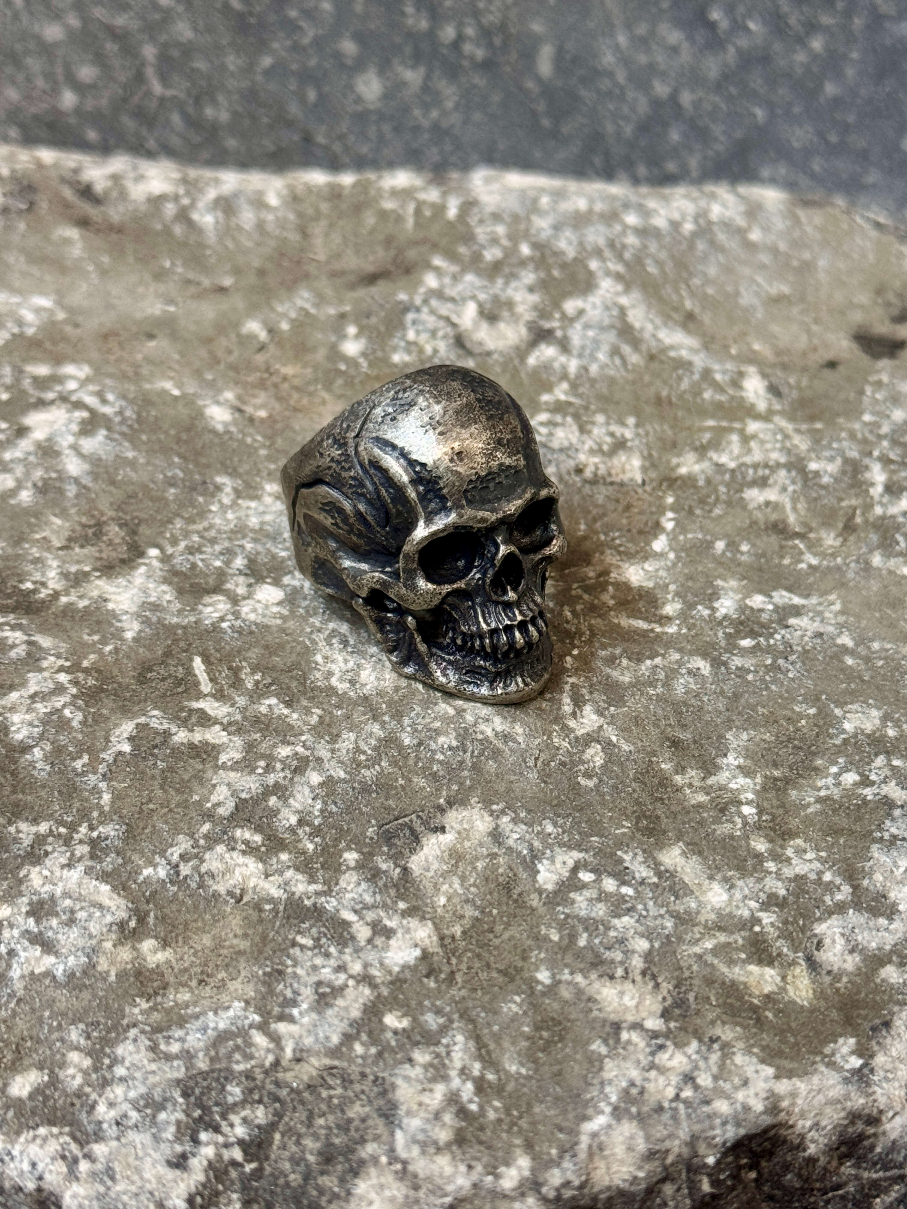 Skull-shaped ring on a textured stone surface